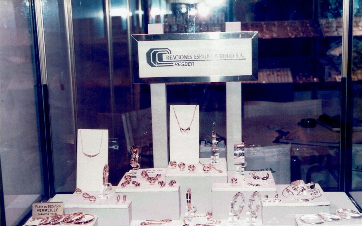 Stand de CRESBER con expositores de joyería en una feria profesional, mostrando colecciones de anillos, collares y pendientes en los años 80-90.